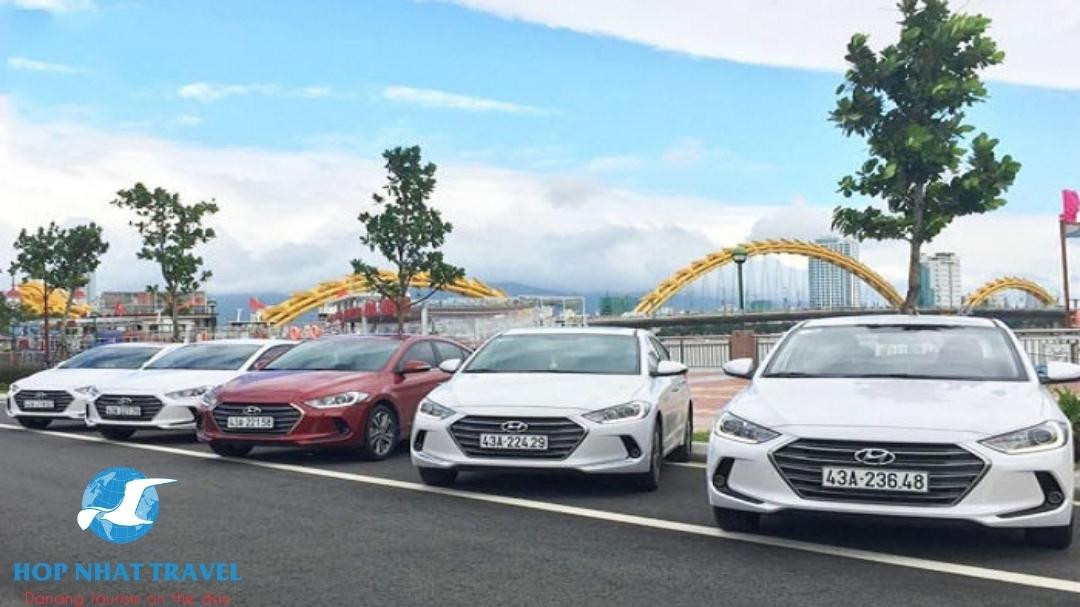 Hình ảnh xe du lịch đang di chuyển trên con đường giữa Đà Nẵng và Hội An, với cảnh quan tự nhiên xung quanh