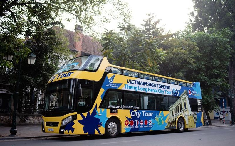 Xe bus 2 tầng Thăng Long Hanoi City Tour màu xanh với hành khách trên tầng thượng, hình ảnh tiêu biểu của xe bus 2 tầng Hà Nội